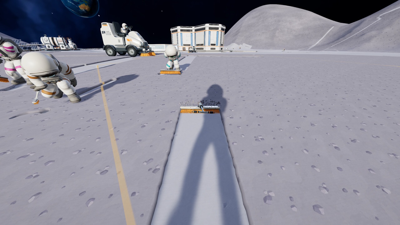 A cleaned strip of lunar ground seen from first person, with astronauts and buildings beyond